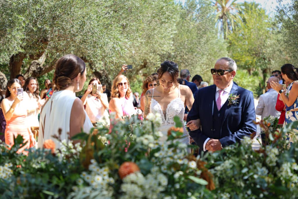 Ceremonia de boda rústica al aire libre en Finca El Vincle, con pareja con arco de flores y paisaje natural al atardecer.